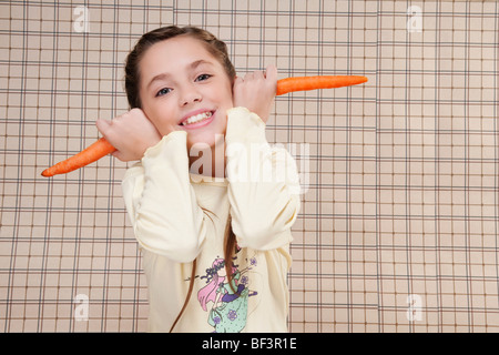 Portrait of a Girl holding carrots sur ses oreilles Banque D'Images