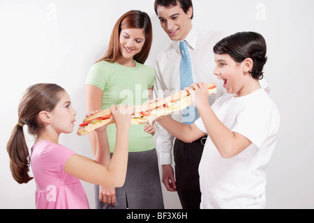 Couple leur fils et leur fille partageant un sandwich sous-marin Banque D'Images