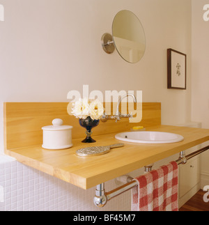 Close-up of petit vase de fleurs sur étagère en bois avec bassin et rail chromé avec red +serviette à carreaux blancs Banque D'Images