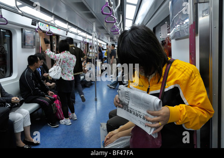 Banlieue d'une femme lisant un journal dans le métro de Beijing, CN Banque D'Images