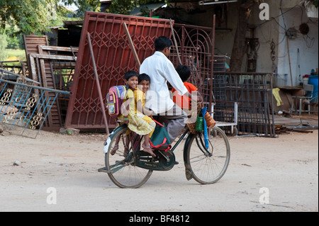 Père indien de prendre ses trois enfants à l'école à bicyclette Banque D'Images