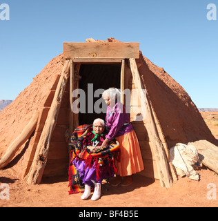 Famille de 2 femmes Navajo à l'extérieur devant la famille Hogan Banque D'Images