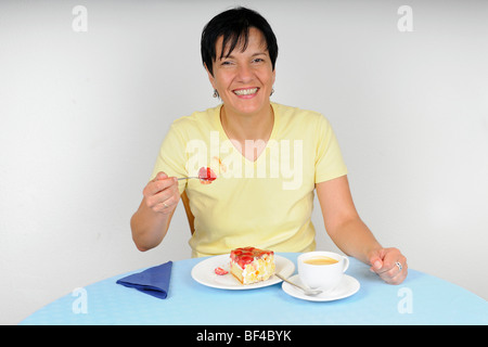 Femme assise à une table et profiter du café et des gâteaux Banque D'Images