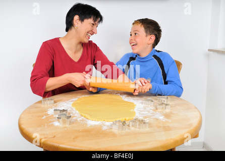 Noël cuisson, mère et fils rouler la pâte à biscuits de Noël avec un rouleau à pâtisserie, emporte-pièce sur th Banque D'Images