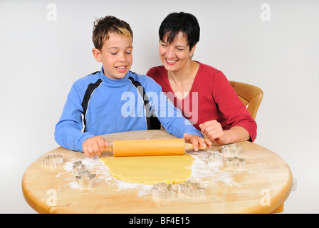 Noël cuisson, mère et fils rouler la pâte à biscuits de Noël avec un rouleau à pâtisserie, emporte-pièce sur th Banque D'Images