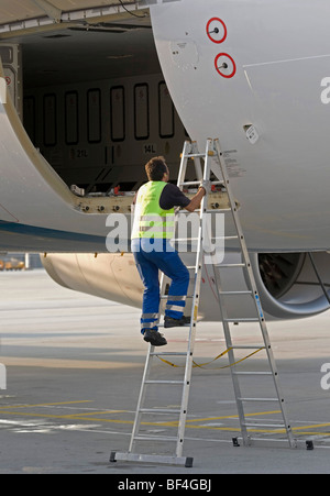 Le personnel au sol de travailler sur une porte de soute, d'un Airbus A330-200 de la compagnie aérienne Oman Air, l'aéroport de Munich, Bavaria, Germany, Europe Banque D'Images