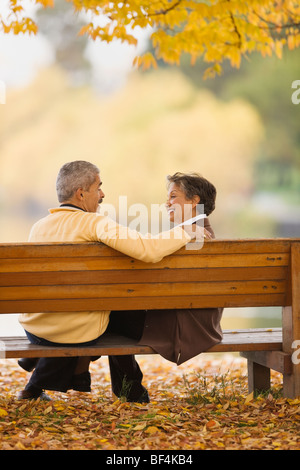 African couple assis sur banc de parc en automne Banque D'Images