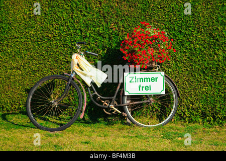 Vélo en face d'une couverture verte avec des fleurs rouges et un panneau "Zimmer Frei", "Chambres à louer" Banque D'Images