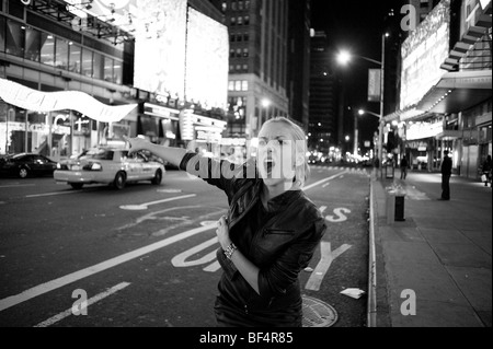 Blonde woman hailing taxi, Times Square New York la nuit Banque D'Images