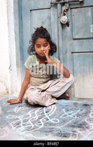 Jeune Indien street girl sitting par une porte dans une rue indienne Banque D'Images