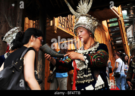 Femme Miao accueillant avec les clients en offrant du vin, de la région de Langde, Miao Leishan County, Qiandongnan Miao et Dong, Guizhou, Chine Banque D'Images