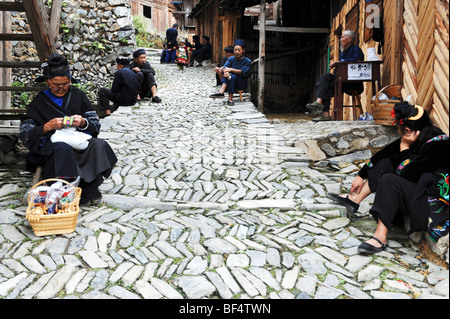 Miao assise à côté de cobblestone road, Upper Village Miao Langde, Leishan County, province de Guizhou, Chine Banque D'Images