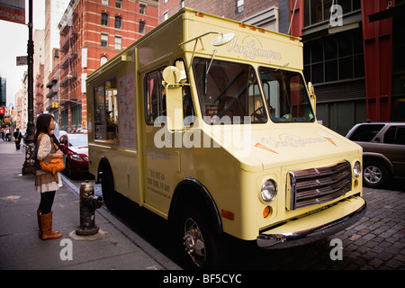 Une jeune femme regarde contemple le menu à l'Artisan Van Leeuwen camion de crème glacée à SoHo, Manhattan, New York, NY, USA Banque D'Images