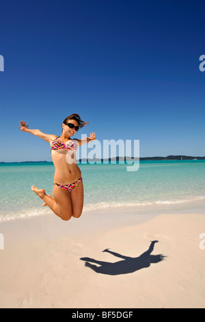 Saut dans l'air, une jeune femme au bord de la mer, image symbolique pour la vitalité, l'ombre, Whitehaven Beach, l'île de Whitsunday, Whitsu Banque D'Images