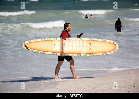 Surfer carrying board sur Muizenberg Beach - Cape Town Banque D'Images