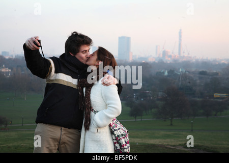 Primrose Hill sur les amoureux s'embrasser et prendre leur propre photo avec la vue de Londres. Banque D'Images