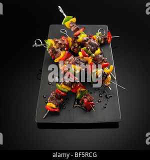 Brochettes de boeuf et de légumes sur les brochettes, sur un fond noir. Banque D'Images