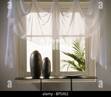 Close-up de voile blanc rideaux sur fenêtre au-dessus de table console avec vases noir Banque D'Images