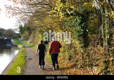 Couple en train de marcher le long de chemin de halage du canal en automne, Hatton serrures, Warwickshire, England, UK Banque D'Images