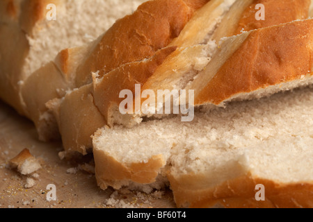 Close up of pain croûté bloomer blanc frais coupé en tranches rugueuses sur un bloc de bois Banque D'Images