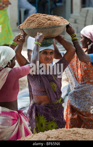Femme indienne travaillant sur les routes, de soulever et de transporter du sable dans un bol. Puttaparthi, Andhra Pradesh, Inde Banque D'Images
