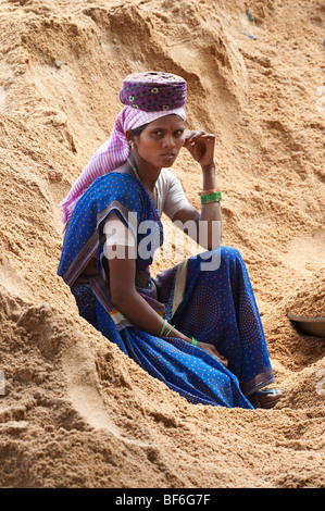 Femme indienne assis dans un tas de sable reposant tout en travaillant sur les routes à Puttaparthi, Andhra Pradesh, Inde Banque D'Images