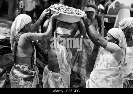 Les femmes indiennes qui travaillent sur les routes, soulever et transporter des pierres dans un bol sur la tête. Puttaparthi, Andhra Pradesh, Inde. Le noir et blanc Banque D'Images