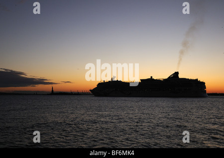 Le navire de croisière, Norwegian Dawn, laissant le port de New York au coucher du soleil avec la Statue de la liberté en arrière-plan. Banque D'Images