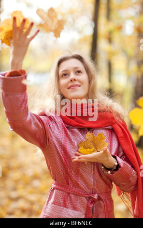 Jeune femme jetant l'automne feuilles d'érable. Banque D'Images