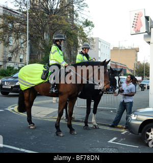 Deux officiers de la police montée à cheval flics parler à un membre du public dans le centre-ville de Swansea, Pays de Galles, Royaume-Uni Banque D'Images