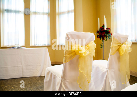 Deux chaises couverts en salle de cérémonie avec une table et s'inscrire, à côté de quelques roses. Banque D'Images