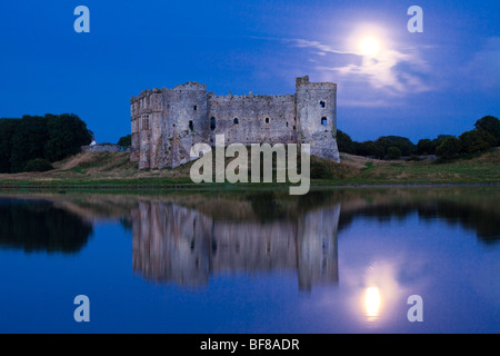 La lune se lève derrière le château de Carew à côté de la rivière Carew à Carew, Pembrokeshire, Pays de Galles, Royaume-Uni Banque D'Images