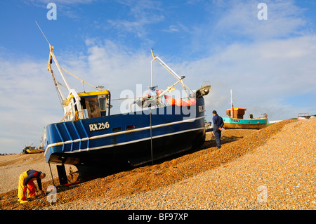 Hastings, East Sussex, Angleterre, Royaume-Uni. Bateau de pêche d'être hissé sur la plage de galets Banque D'Images