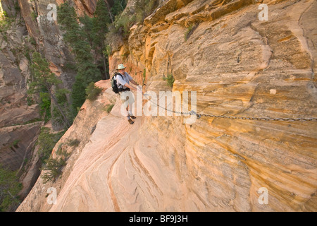 Pour obtenir de l'aide l'aide de chaînes randonneur le long de falaise sur sentier Hidden Canyon Zion Canyon ci-dessus à Zion National Park, Utah Banque D'Images