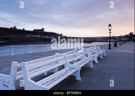 Une vue du coucher de bancs blancs dans une ligne, sur la jetée ouest à l'entrée du port de Whitby, North Yorkshire. Banque D'Images