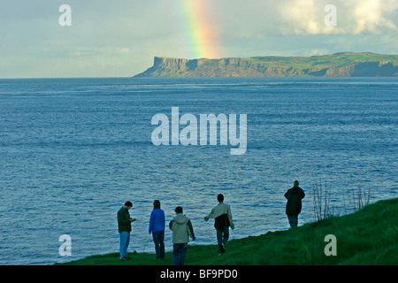 Les gens qui regardent un arc-en-ciel juste au-dessus de la tête de Carrick-a-Rede Island, dans le comté d'Antrim, en Irlande du Nord Banque D'Images