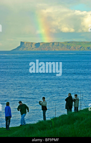 Les gens qui regardent un arc-en-ciel juste au-dessus de la tête de Carrick-a-Rede Island, dans le comté d'Antrim, en Irlande du Nord Banque D'Images