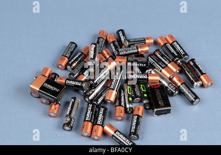 Une pile de piles AA empilés sur une table tourné sur un fond bleu. Les batteries prêt pour le recyclage. Banque D'Images