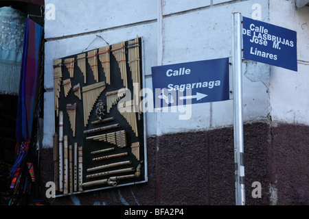 Signe pour Marché des sorcières sur coin de Calles Sagarnaga et Linares, instruments de musique hanging sur mur derrière, La Paz, Bolivie. Banque D'Images