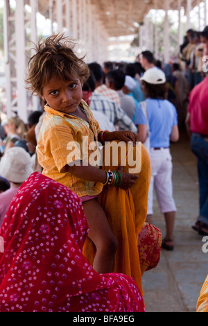 Petit enfant à cheval sur les épaules de la mère à la foire de chameau à Pushkar Inde Banque D'Images