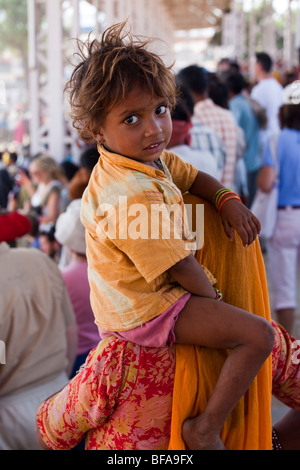 Petit enfant à cheval sur les épaules de la mère à la foire de chameau à Pushkar Inde Banque D'Images