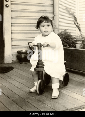 Infant Girl Riding Scooter Three-Wheel on Porch Banque D'Images