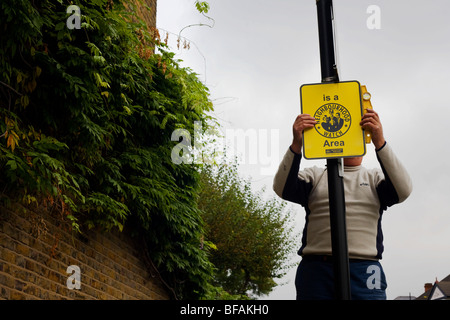 Un employé de Lambeth pend un nouveau signe de surveillance de quartier sur un lampadaire de l'arrondissement de Lambeth à Londres. Banque D'Images