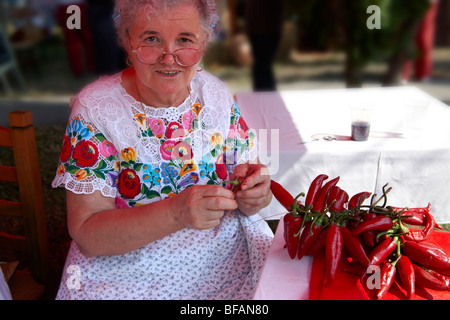 Les vieilles femmes en robe traditionnelle à l'paprka Kalocsa festival cordes faisant de piments. Kalocsa, Hongrie Banque D'Images