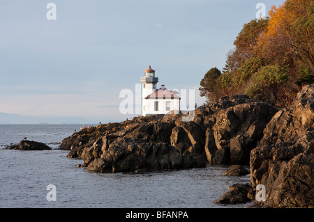 Four à chaux phare, entouré par la côte rocheuse, est éclairé par la lumière chaude d'un coucher du soleil à la fin de l'automne. Banque D'Images