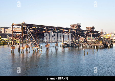 Vue sur la rivière d'après-midi sur l'acier rouillé éloquent historiquement squelette d'un incendie a ravagé pier Red Hook waterfront Brooklyn NY Banque D'Images