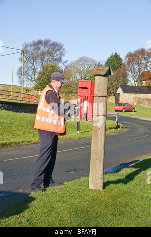 Postman la collecte des lettres d'une boîte de poste rural près de Reeth, Swaledale. Banque D'Images