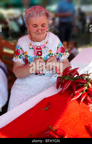 Les vieilles femmes en robe traditionnelle à l'paprka Kalocsa festival cordes faisant de piments. Kalocsa, Hongrie Banque D'Images
