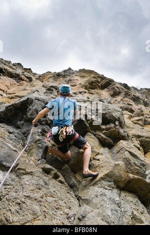 Un male rock climber en tirant la corde au clip dans à la protection. Point de lave, rivière Tieton Escalade, Cascade Mountain, Washington. Banque D'Images