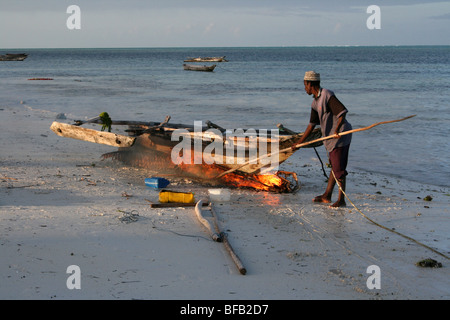 Brûler les algues marines la coque d'un bateau sur la plage de Jambiani, Zanzibar Banque D'Images